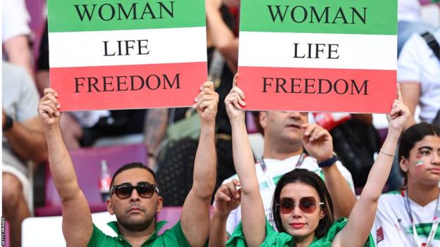 Two Iran fans holding up 'Women Life Freedom' banners